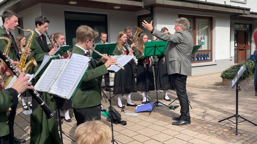 Franz Schindler dirigiert die Grünen Jäger beim Maibaumstellen in der Ortsmitte von Neusatz